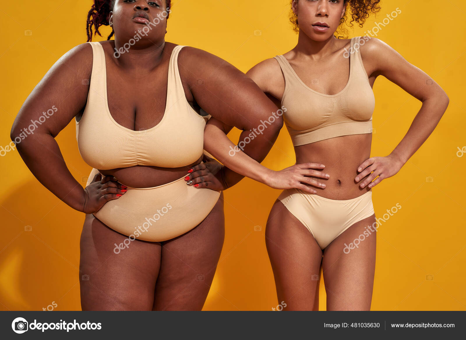 Cropped shot of two confident african american female models in underwear  with different body weight holding hands on waist, standing together  isolated over yellow background Stock Photo by ©LanaStock 481035630