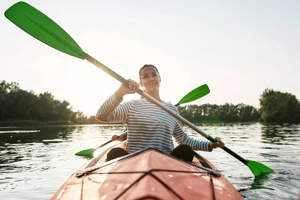 Giovane donna attiva che sembra allegra mentre cammina in kayak insieme al suo amico in una giornata estiva — Foto Stock