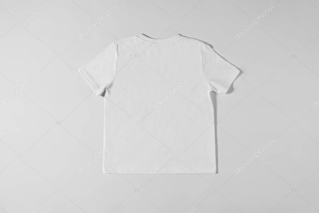 White tee-shirt lying on a light background. Light background with designer unisex t-shirt for men and women. Clothes without logos and inscriptions. Simple stuff concept