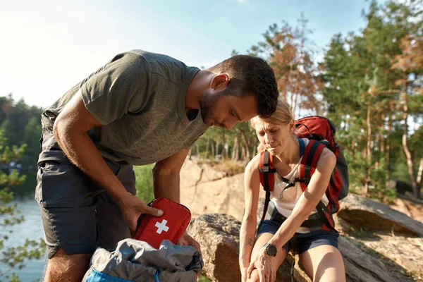Young man using first aid kit on injured leg — Stock Photo, Image
