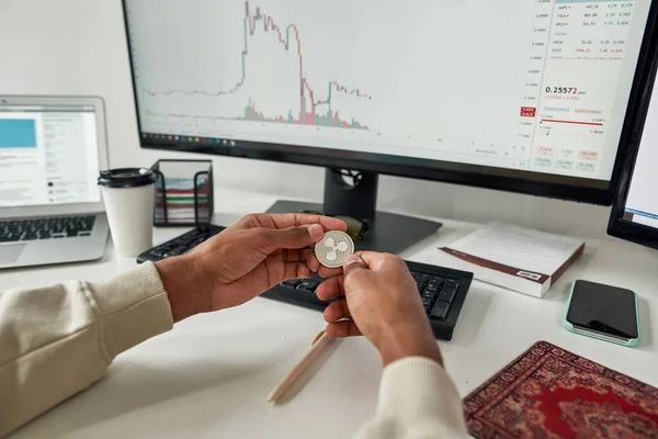 Hands of male trader holding Ripple XRP cryptocurrency token, investing in stock market to exchange it while trading using pc from home — Stock Photo, Image