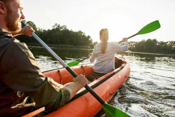 夏天的一天，一个活跃的年轻女子和她的男朋友在湖中划船的倒影 — 图库照片