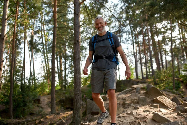 Feliz homem caucasiano de meia idade trekking na floresta — Fotografia de Stock