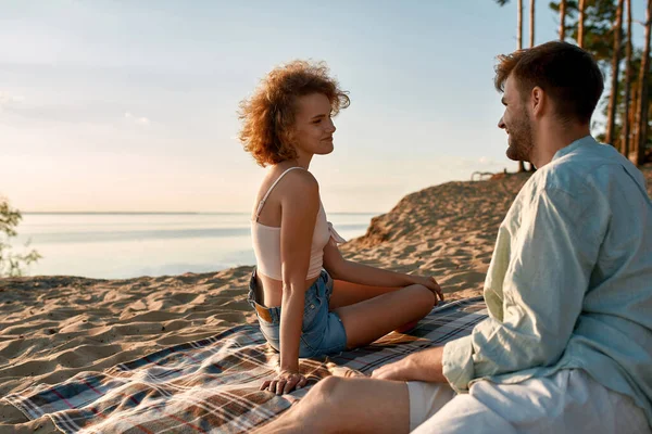 Jovem casal caucasiano feliz sentado na praia ensolarada — Fotografia de Stock