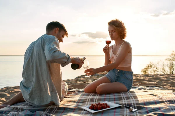 Jovem casal caucasiano enchendo copos com vinho tinto — Fotografia de Stock