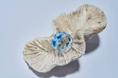 Üzerinde mavi diş minesi olan el yapımı gümüş bir yüzük. Deniz kabuğundan izole edilmiş.