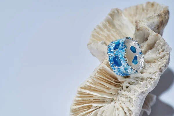 Primer plano de anillo hecho a mano de metal plateado con esmalte azul en la parte superior dispuesto en concha aislada sobre fondo claro —  Fotos de Stock
