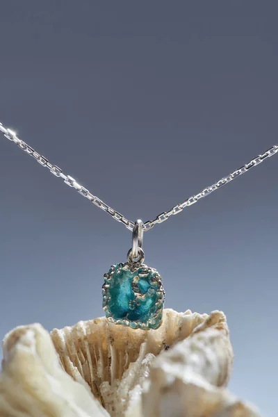 Beautiful pendant with chain made of silver and turquoise epoxy resin inside arranged with a seashell isolated over gradient background — Stock Photo, Image