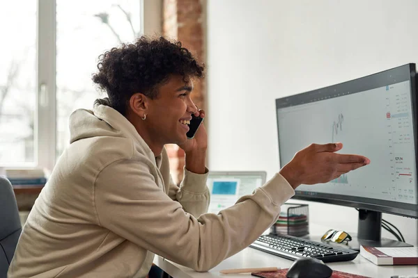 Retrato de un joven comerciante feliz haciendo una llamada, discutiendo el mercado de valores mientras mira gráficos, el comercio desde el hogar —  Fotos de Stock