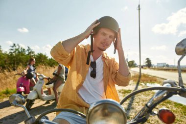 Neşeli genç beyaz adam kaskını takıyor.