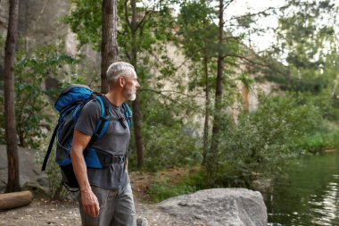 Yakışıklı orta yaşlı beyaz adam göle bakıyor.