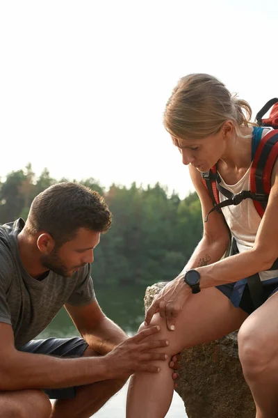 Junge Kaukasierin sitzt mit verletztem Bein auf Felsen — Stockfoto