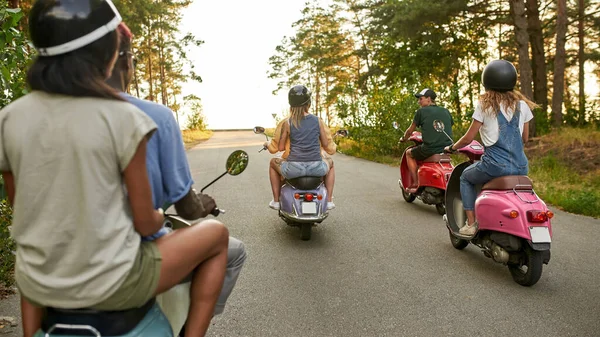 Visão traseira de jovens amigos multirraciais montando scooters retro — Fotografia de Stock