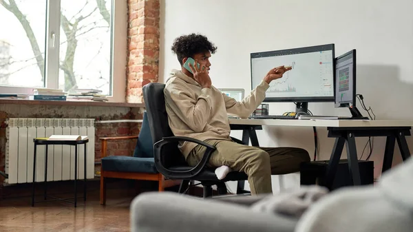 Beschäftigter junger männlicher Händler telefoniert mit dem Kunden, diskutiert über den Aktienmarkt, während er zu Hause am Schreibtisch sitzt — Stockfoto