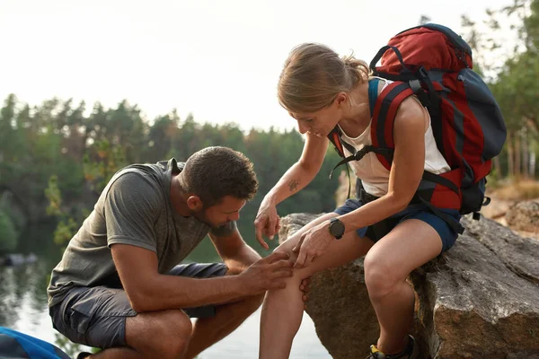 Junge Kaukasierin sitzt mit verletztem Knie auf Felsen — Stockfoto