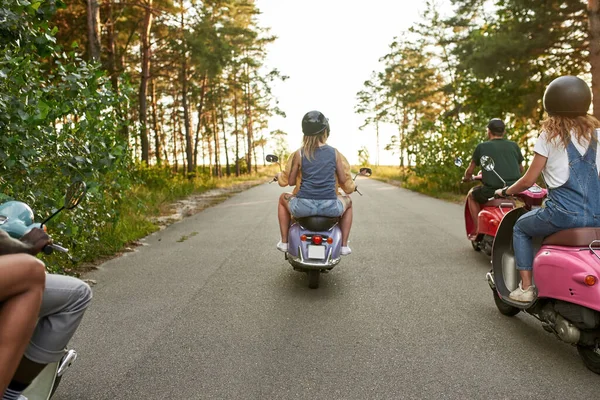 Visão traseira de jovens amigos multirraciais montando scooters — Fotografia de Stock