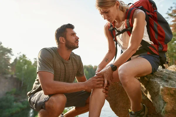 Junger Kaukasier kontrolliert verletztes Bein einer Frau — Stockfoto