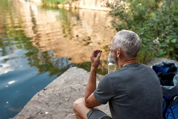 Homem caucasiano de meia idade comendo e bebendo água — Fotografia de Stock