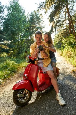 Şirin, genç, beyaz, güneşli doğada scooter süren çift.