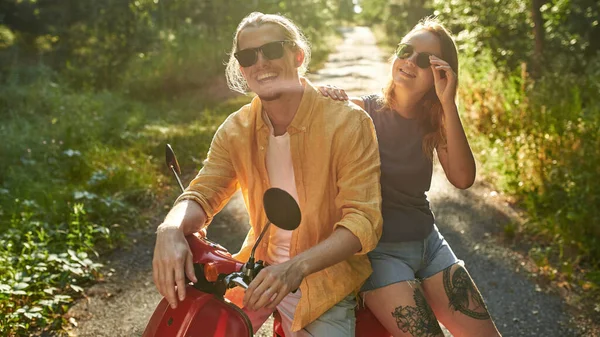 Sorrindo jovens amigos caucasianos sentados em scooter — Fotografia de Stock