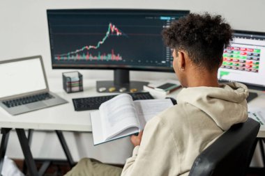 Erkek tüccar öğrenim görürken evde bilgisayar ticareti yapıyor.