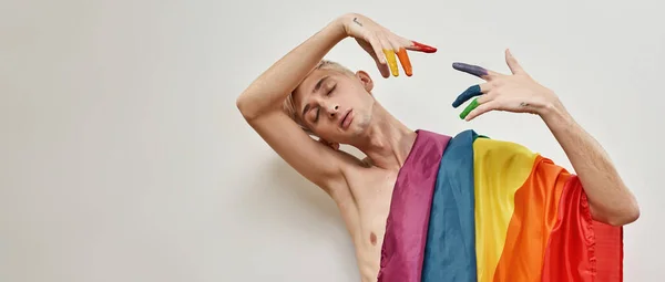 Lgbtqi bayrağıyla genç ve sanatçı bir transseksüel. Renkli gökkuşağı renginde parmaklarıyla başının yakınında el ele tutuşuyor. Işık arkaplanı üzerinde izole edilmiş pozlar veriyor. — Stok fotoğraf