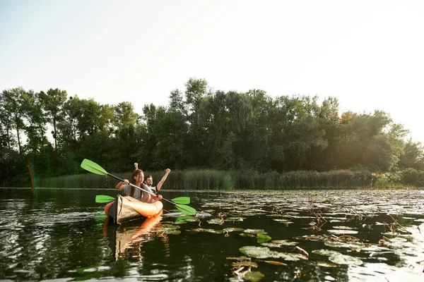 Vidám fiatal vegyes pár együtt töltik az idejüket, kajakoznak a folyón, vad természettel körülvéve. — Stock Fotó