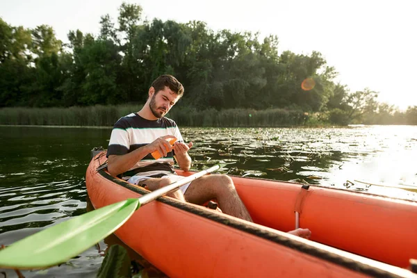 Gericht jonge man die zonnebrandcrème bescherming tijdens het kajakken op de rivier buiten — Stockfoto