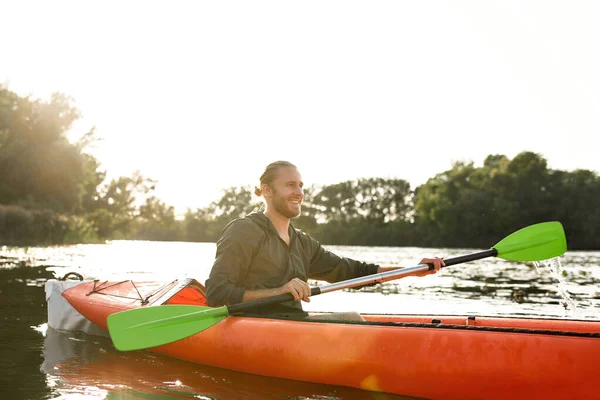 Vrolijke jongeman kajakken op de rivier, paddle vasthouden, lachen op een zomerse dag — Stockfoto