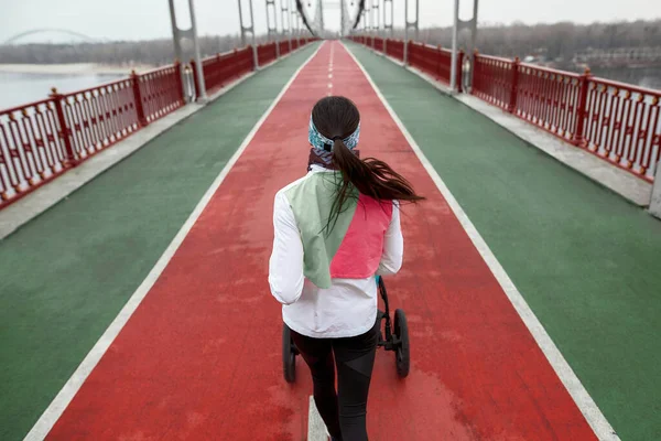 Visão de alto ângulo de atleta jovem atleta em treinamento de sportswear com um carrinho em uma ponte na cidade — Fotografia de Stock