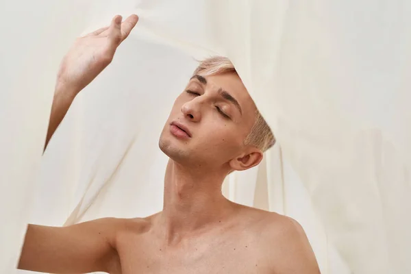 Portret zmysłowego młodego transseksualisty z makijażem pozowanie z zamkniętymi oczami na jasnym pastelowym tle — Zdjęcie stockowe
