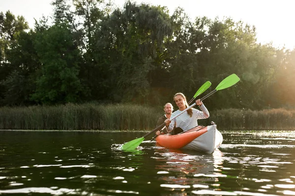 Actief jong Kaukasisch paar kajakken op de rivier met bomen op de achtergrond — Stockfoto