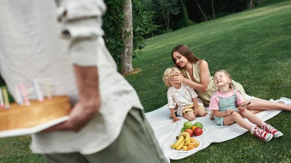 Far förberedde en överraskning åt sin son. Familjen kopplar av, har picknick i parken, firar barnens födelsedag tillsammans utomhus en sommardag — Stockfoto