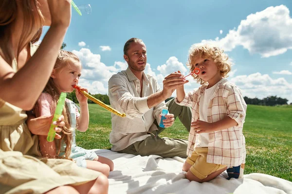 Lindos niños pequeños que se divierten mientras pasan tiempo con sus padres, la familia de picnic en la naturaleza en un día de verano —  Fotos de Stock