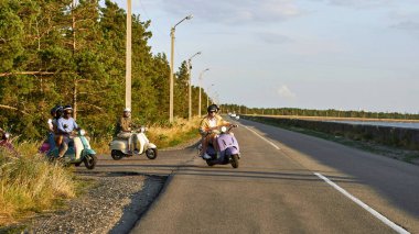Moto scooterlı arkadaşlar şehrin dışındaki bir yolda virajda hareket halindeler.