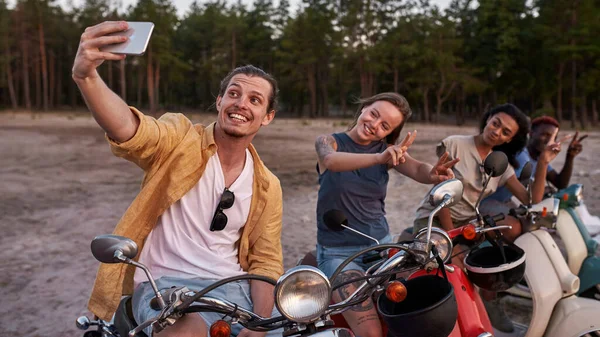 一群年轻的朋友，骑摩托车的人一边笑着一边自私自利，坐在城外的摩托车上 — 图库照片