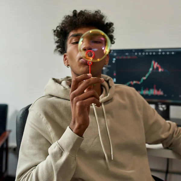 Ethnic male trader blow bubbles working on market