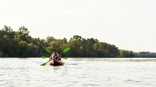 Aktív fiatalok eveznek együtt a folyón, körülvéve nyári természettel egy hétvégén — Stock Fotó
