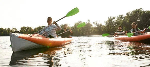 Avontuurlijke jongeren die plezier hebben, samen kajakken op een rivier, een weekend buiten doorbrengen op een zomerse dag — Stockfoto