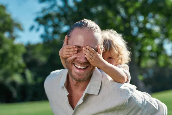 Küçük oğlunun, bir yaz günü parkta oynarken gözlerini elleriyle kapadığı portreyi kapat. — Stok fotoğraf
