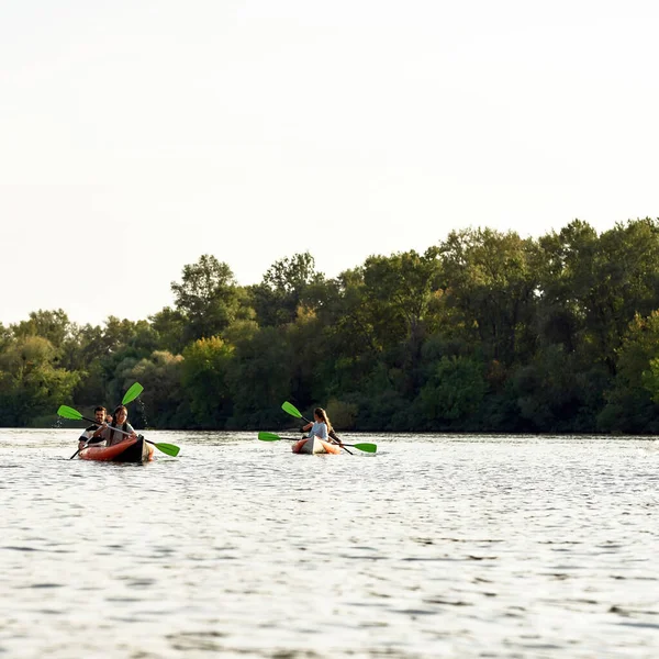 Aktif gençler hafta sonları etrafı yaz doğasıyla çevrili bir nehirde birlikte kürek çekiyorlar.