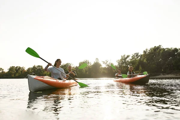 Vidám fiatalok kajakoznak együtt a folyón, a hétvégét a szabadban töltik egy nyári napon. — Stock Fotó