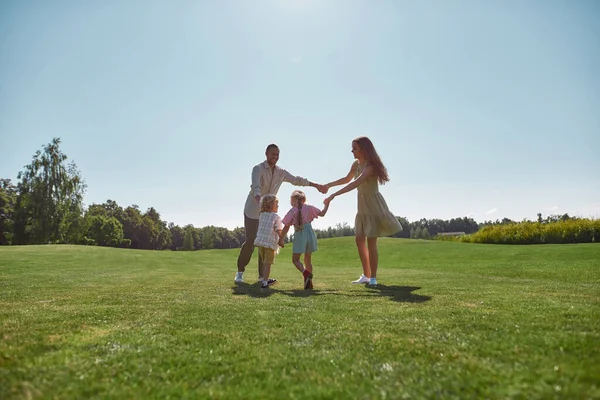 Mutlu bir aile, boş zamanların tadını çıkarıyor, iki küçük çocukla vakit geçiriyor, bir yaz günü yeşil parkta kız ve erkek. — Stok fotoğraf