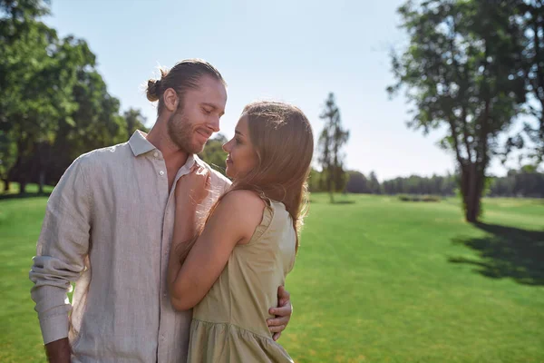 Портрет романтической молодой пары, смотрящей друг на друга, позирующей на открытом воздухе, стоя в парке — стоковое фото