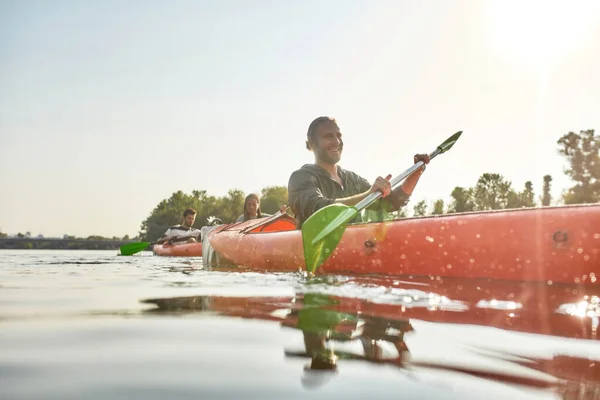 Joven activo mirando entusiasta mientras kayak en un barco en un río en un día de verano — Foto de Stock