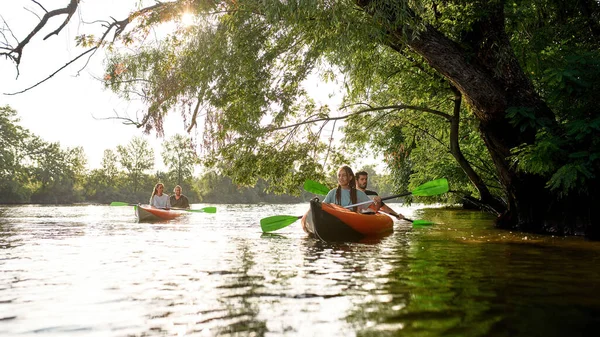Aktif insanlar güneşli bir günde nehirde kano kullanmaktan zevk alıyorlar.