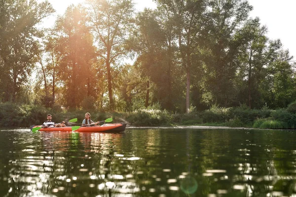 Twee jonge vrienden varen samen op een meer omgeven door vredige zomerse natuur — Stockfoto