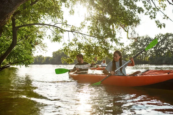 Együtt kajakoznak a folyóban, tavasszal vagy nyáron fákkal körülvéve, együtt töltik az időt a szabadban. — Stock Fotó