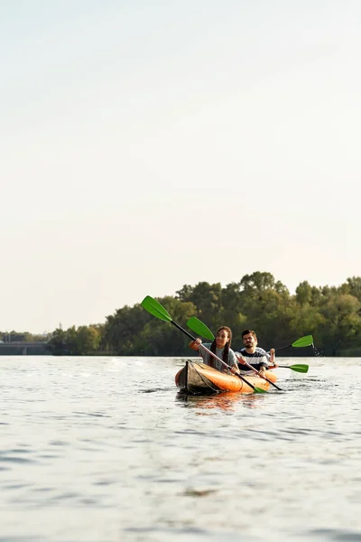 Giovani sportivi che remano insieme su un fiume, trascorrendo il fine settimana all'aperto in una giornata estiva — Foto Stock