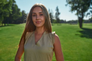 Parkta durup poz verirken gülümseyen güzel beyaz kadın portresi.